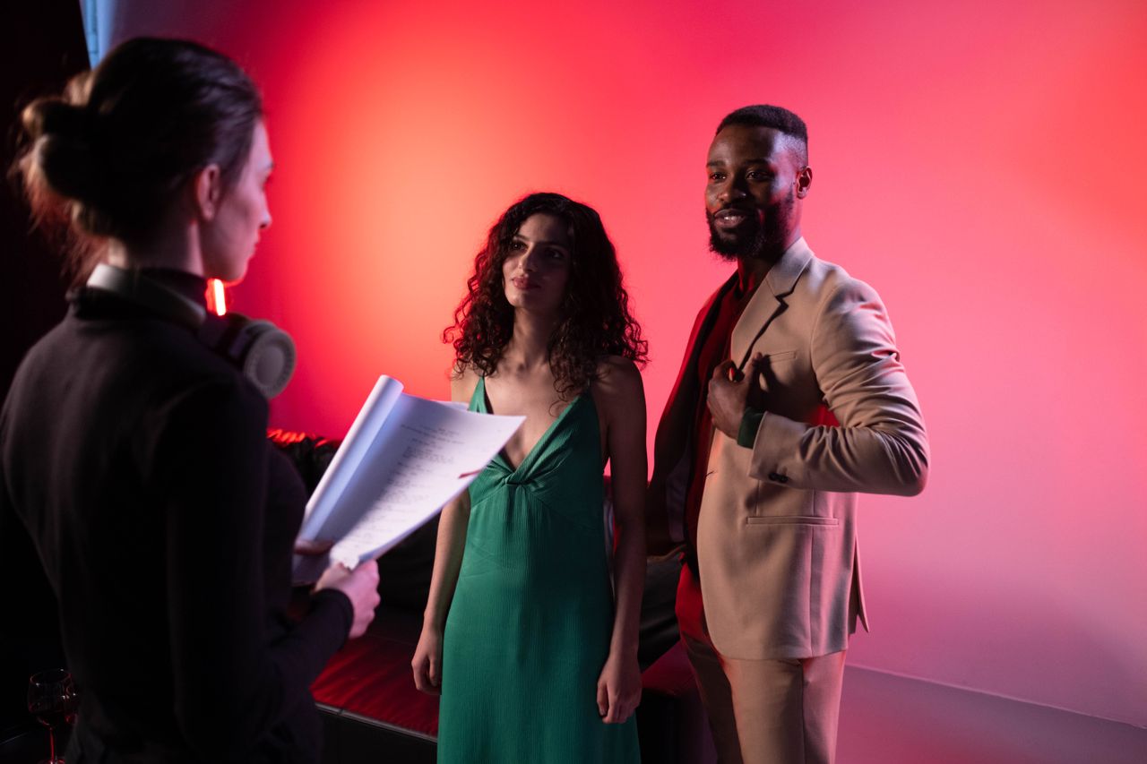 Actors discussing script during a studio shoot with dramatic lighting.